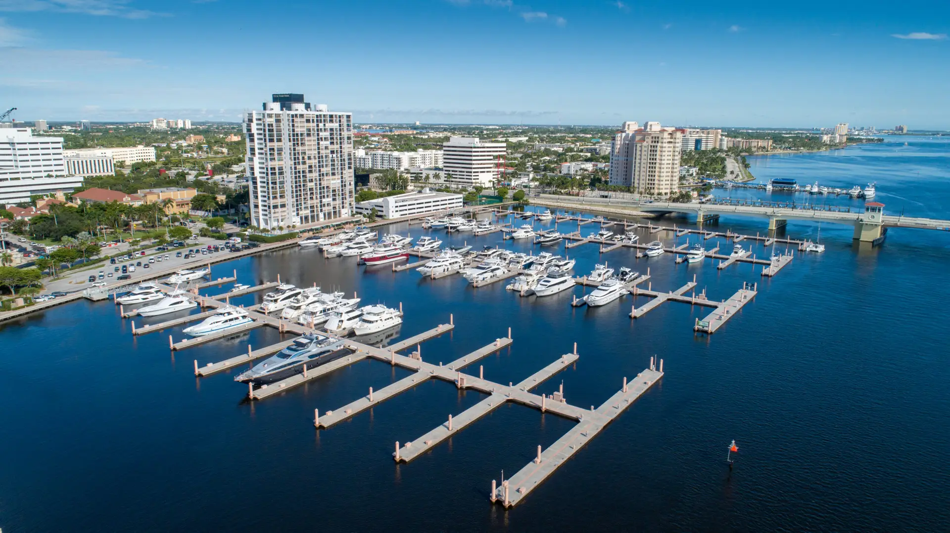 A marina with boats docked and city buildings in the background.